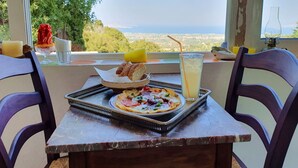 Une table sur laquelle se trouve un plateau contenant une pizza, une boisson et un dessert, le tout placé devant un paysage pittoresque.