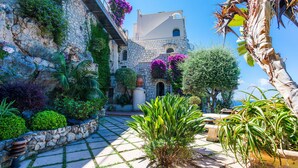 A stone building with a balcony, surrounded by lush greenery and potted plants. - LE CAP DE NICE VI4150 by RIVIERA HOLIDAY HOMES (Niza)