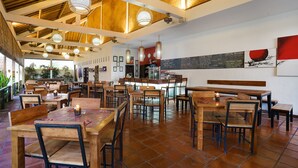 Un restaurante con mesas y sillas de madera, una zona de bar y un menú en la pizarra.