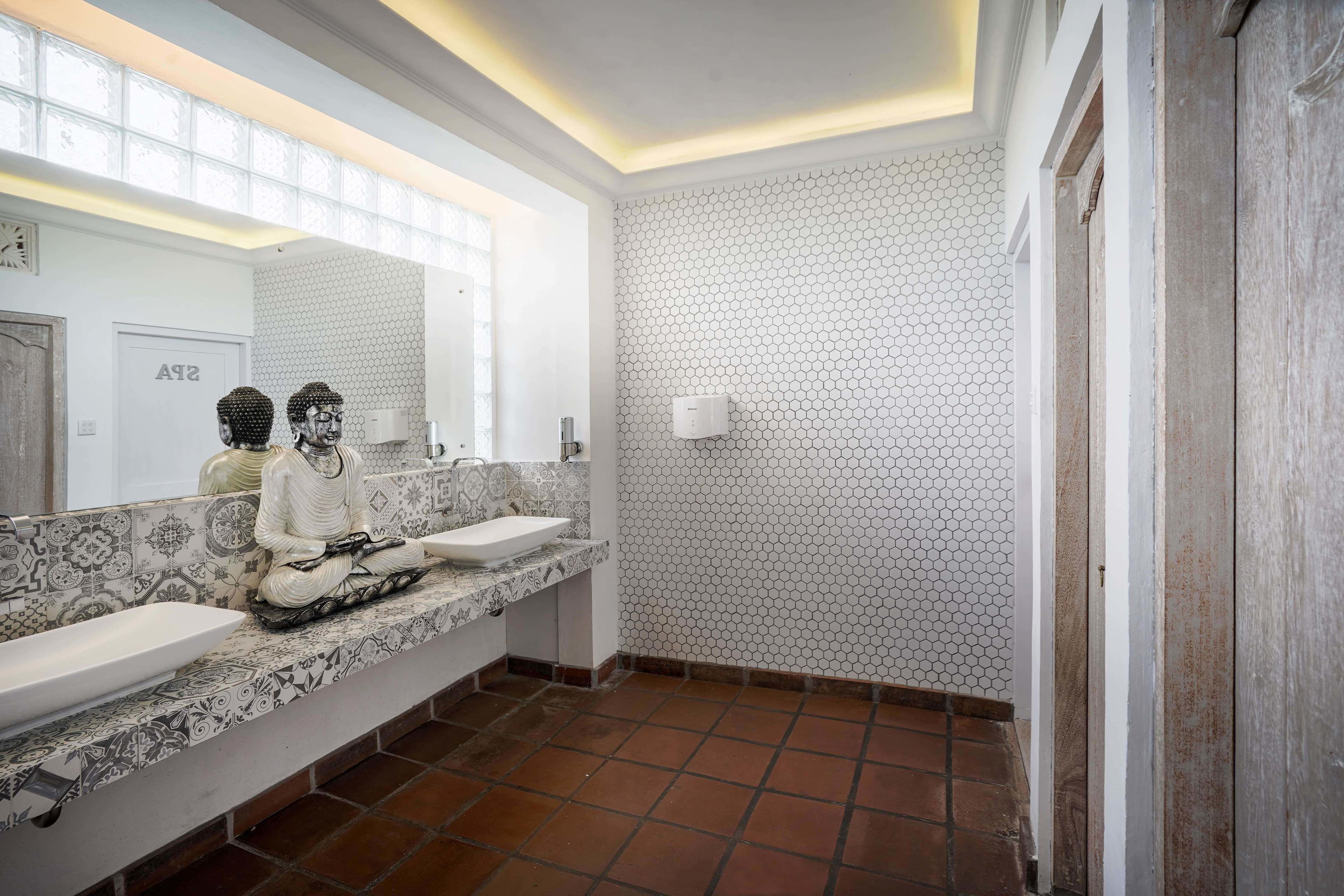 Une salle de bain avec deux lavabos, un miroir et un mur orné d’un motif hexagonal.