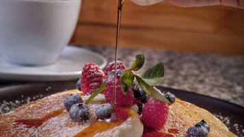 Ein Teller mit Pfannkuchen, Beeren und Ahornsirup.