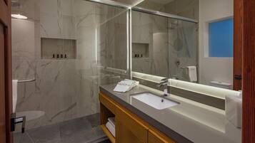 A modern bathroom with a large mirror, a sink, and a shower area.