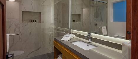 A modern bathroom with a large mirror, a sink, and a shower area.