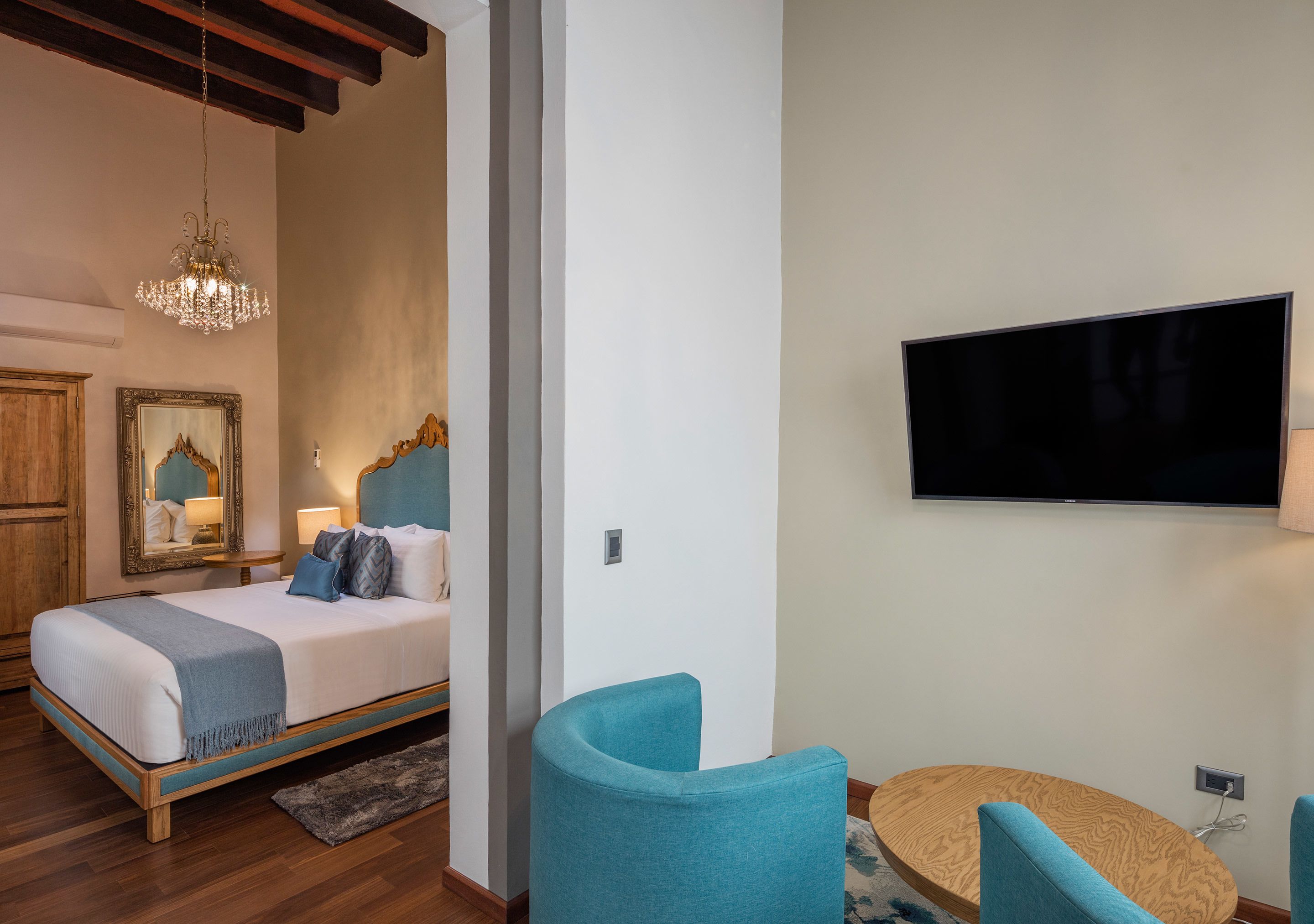 A bedroom with a bed, a television, and two chairs.