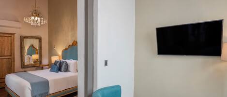 A bedroom with a bed, a television, and two chairs.