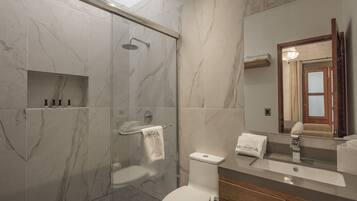 A modern bathroom with a glass-enclosed shower, a toilet, and a sink with a vanity.