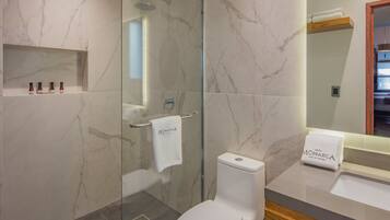 A modern bathroom with a glass shower enclosure, a white toilet, and a vanity with a wooden countertop.