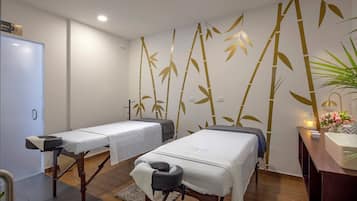 Relax in a serene space with two massage therapy beds, a bamboo-themed wall, and a desk with a sink.