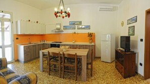 Eine kompakte Küche mit Esstisch, Stühlen, einem Kühlschrank und einem Fernseher.