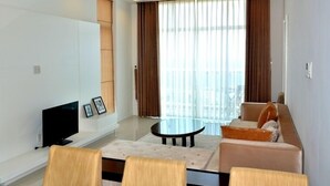 Una sala de estar moderna con un televisor de pantalla plana, una mesa redonda de centro y un sofá.