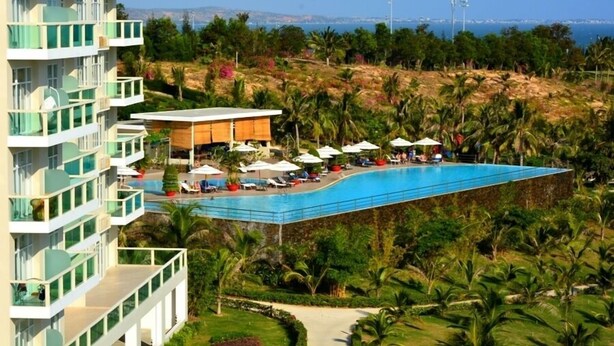 Un resort con piscina, palmeras y vista al mar.