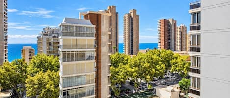 A high-rise residential building with multiple balconies, a rooftop terrace, and a view of the sea.