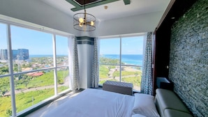 A bedroom with a large window offering a view of the city and ocean. - Lux. 2BR condo + 2 pools, woow oceanviews, Gym, Beach,near Mactan Newtown, Tours (Lapu-Lapu City)