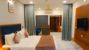 A hotel room with a bed, bedside table, TV, and a view of the bathroom and hallway.