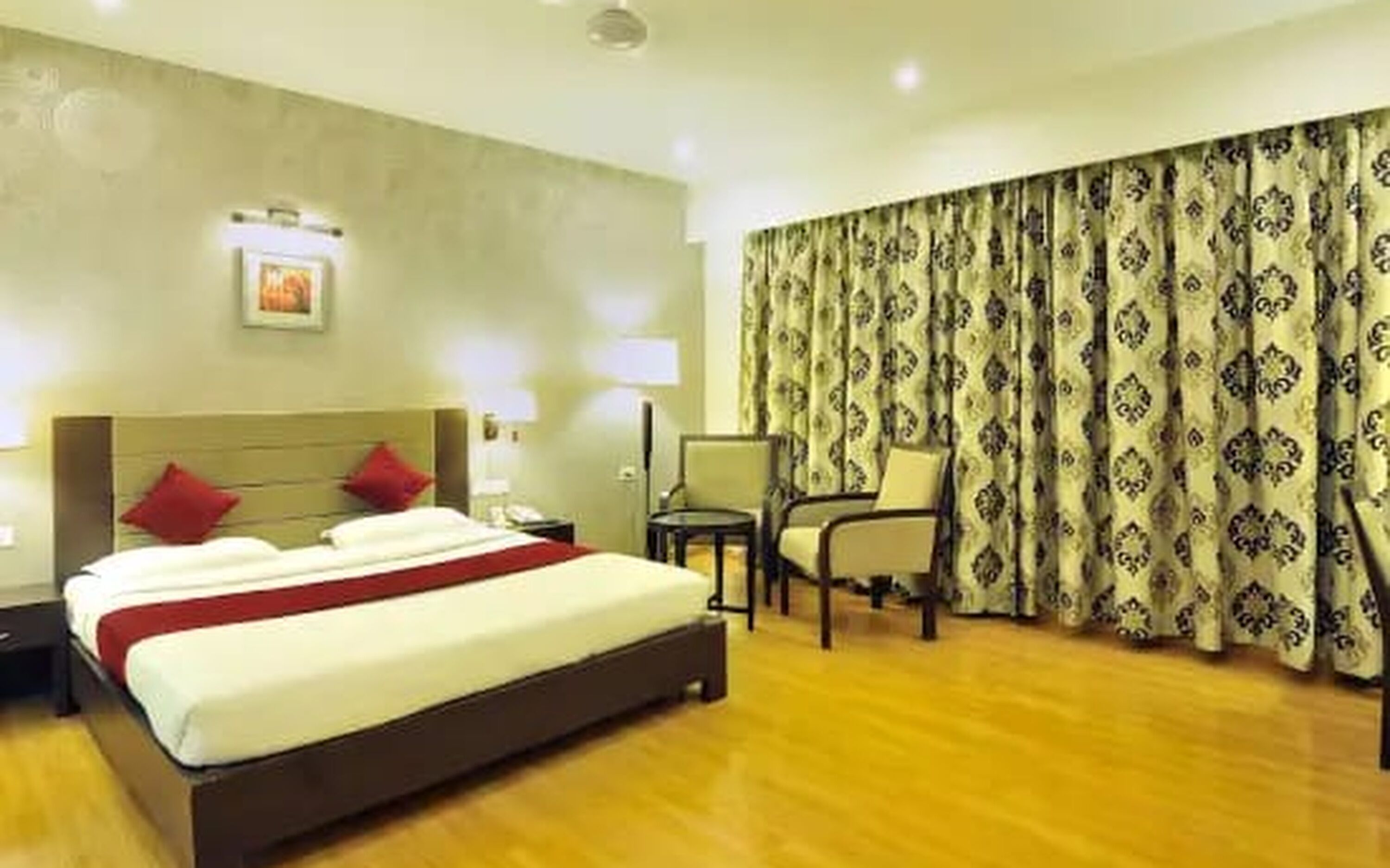A hotel room with a bed, nightstands, a chair, and a large window with curtains.