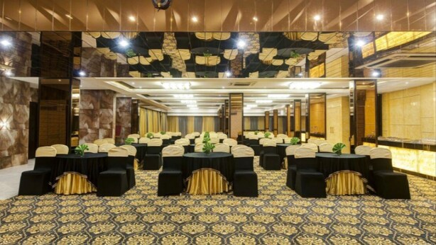 A conference room with multiple tables and chairs, a patterned carpet, and a mirrored wall.
