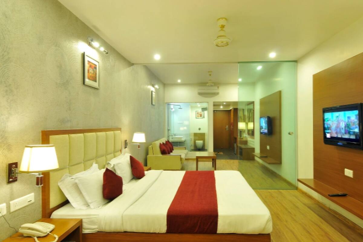 A hotel room with a large bed, bedside lamps, a TV, and a phone on the nightstand.