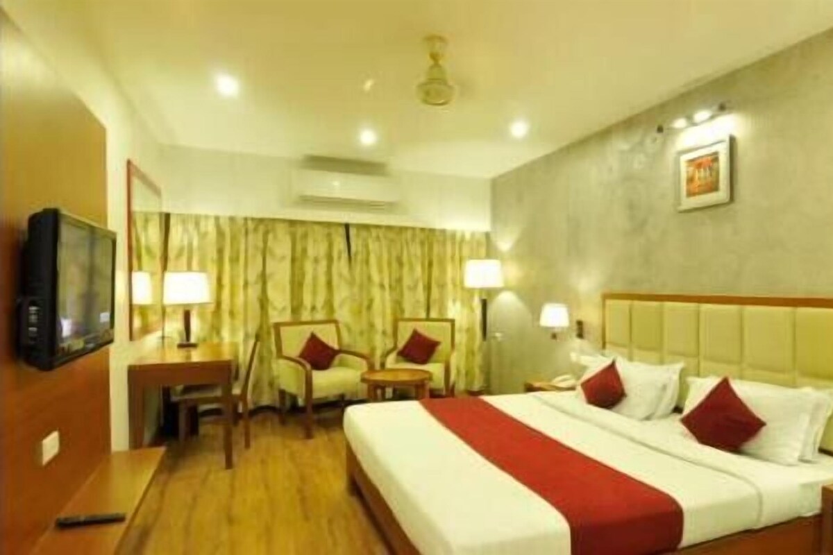 A hotel room with a bed, two bedside tables, a television, a desk, and a chair.