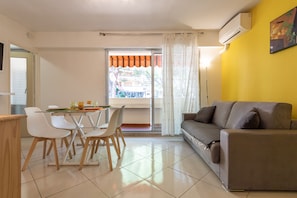 A modern living room with a sofa, dining table, chairs, and a window with curtains. - LOVELY STUDIO 1 ROOM- between Monaco and Menton (Roquebrune-Cap-Martin)