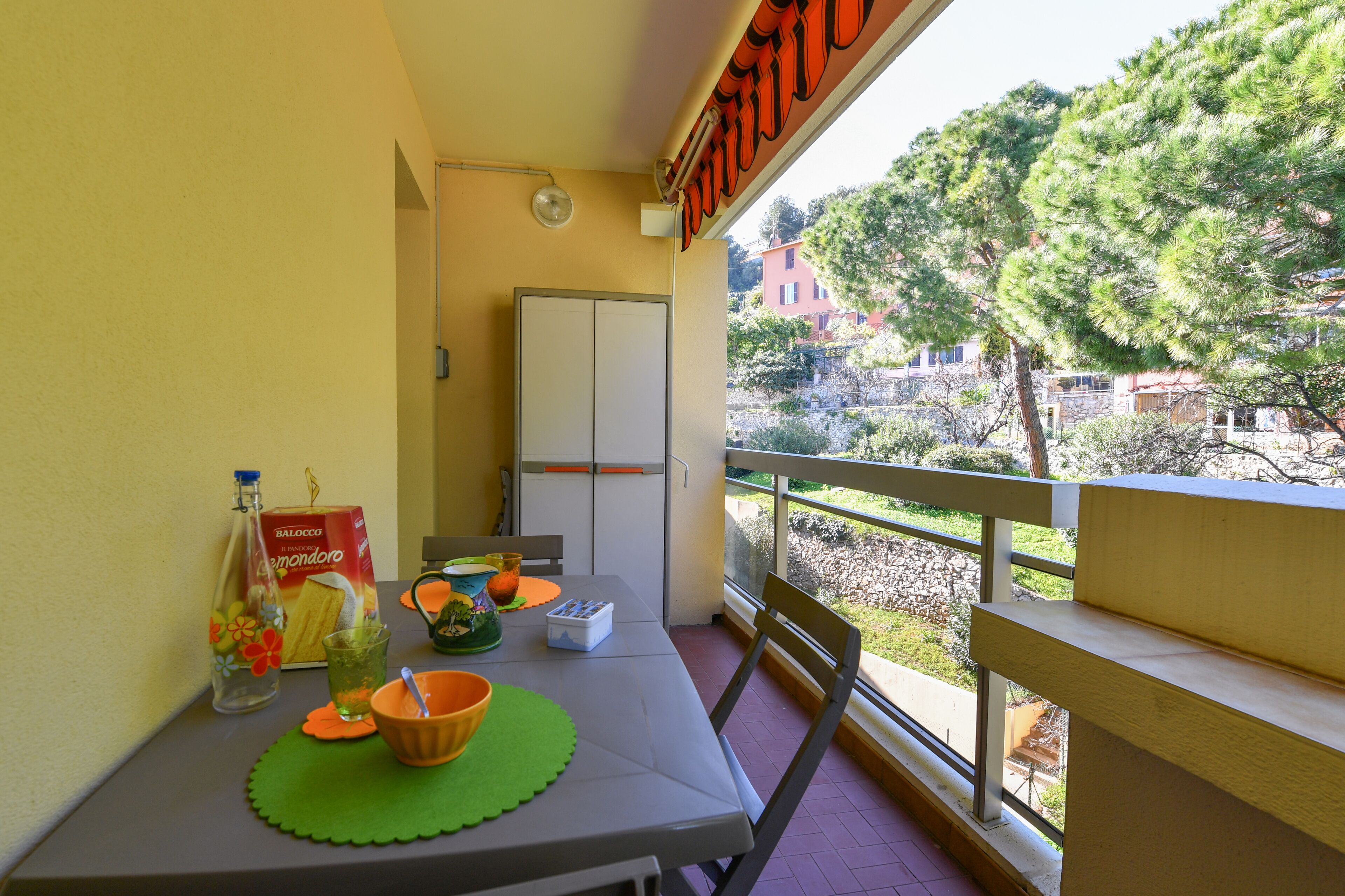 A balcony with a table set for dining, a bottle of water, and a box of lemonades.