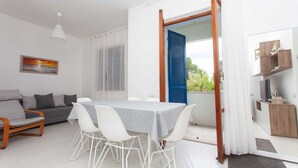 Ein modernes Wohnzimmer mit Esstisch, weißen Stühlen, einem grauen Sofa und einem Holzstuhl.