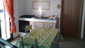 Uma cozinha compacta com fogão, pia e mesa de jantar com toalha de mesa florida.