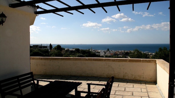 Um terraço com vista para o mar e para a paisagem urbana.