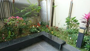 A garden with a black tiled bench, various flowering plants, and a bamboo fence. - Feng Chia Love Heart (Taichung)