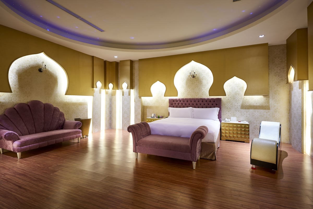 Quarto luxuoso com uma cama grande, dois sofás e uma mesa de cabeceira.