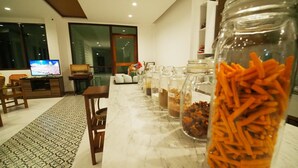 Un salon moderne avec une table en marbre, un téléviseur et divers pots contenant des en-cas.