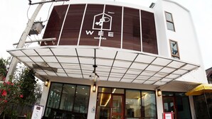 Une auberge de jeunesse au design moderne, reconnaissable à son panneau « Wee Hostel » bien visible, à son entrée abritée et à son petit espace extérieur aménagé en coin salon.