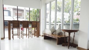 Une pièce spacieuse avec de grandes fenêtres, un banc en bois et une table ornée de vases décoratifs.