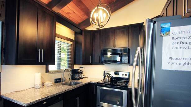A kitchen with dark wood cabinets, stainless steel appliances, a granite countertop, and a window with blinds. - Tahoe Olympic Condo | Carson Valley Views (Stateline)