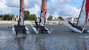 Trois voiliers sur une plage de sable, sous un ciel dégagé.