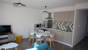 Une cuisine moderne avec des armoires blanches, un dosseret en carreaux disposés en motif chevron et un coin repas avec une table et des chaises blanches.