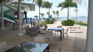 Un área de comedor al aire libre con mobiliario de mimbre y vistas al mar.