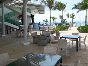 Un espace extérieur aménagé pour les repas, avec des meubles en osier et une vue sur la mer.