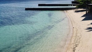 Uma praia com águas turquesa cristalinas e um píer de madeira.