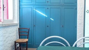 A room with a blue wardrobe, a wooden chair, a white table, and a window with pink blinds. - N082 - Numana, villa with right garden (Numana)