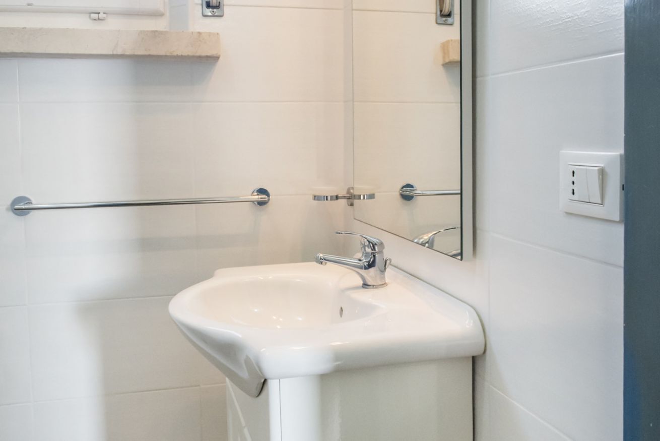 A bathroom with a white sink, a mirror, and a towel rack.