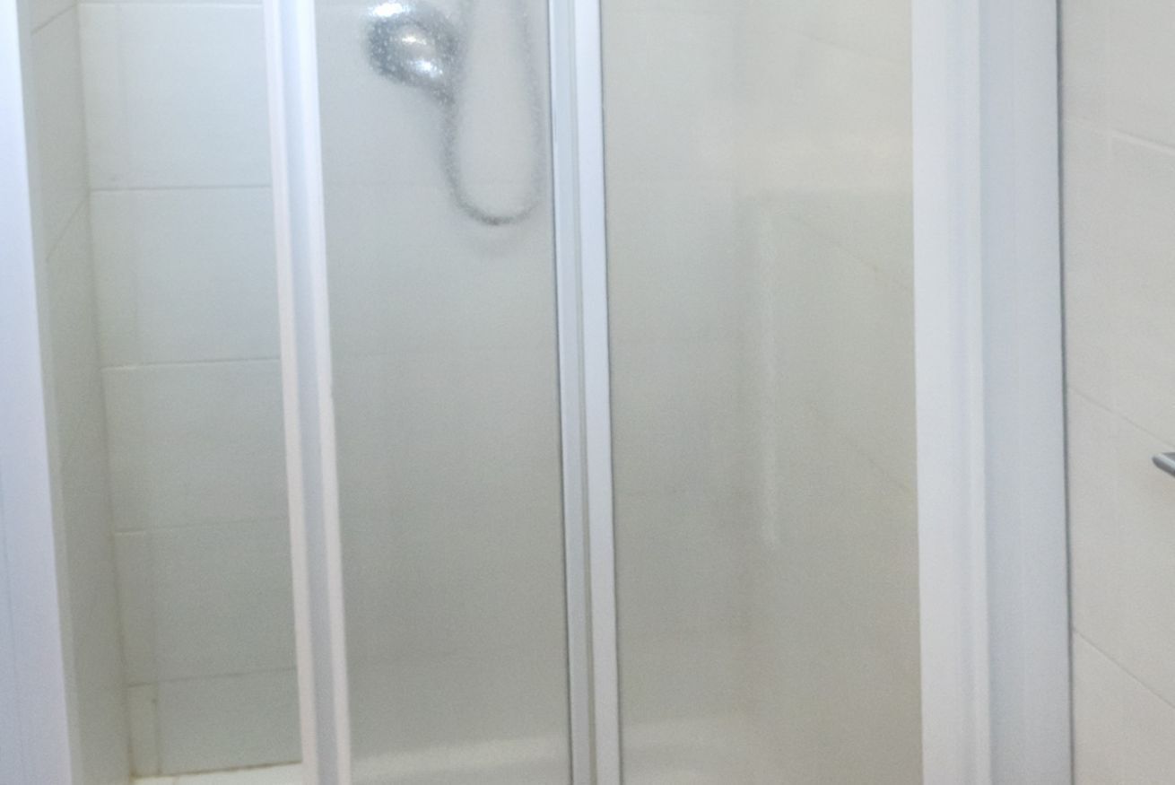A glass-enclosed shower stall with a showerhead.