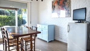 A dining area with a wooden table and chairs, a light blue cabinet, a white refrigerator, and a painting on the wall. - N082 - Numana, villa with right garden (Numana)