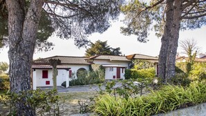 A white building with red shutters and a tiled roof, surrounded by trees and shrubs. - N082 - Numana, villa with right garden (Numana)