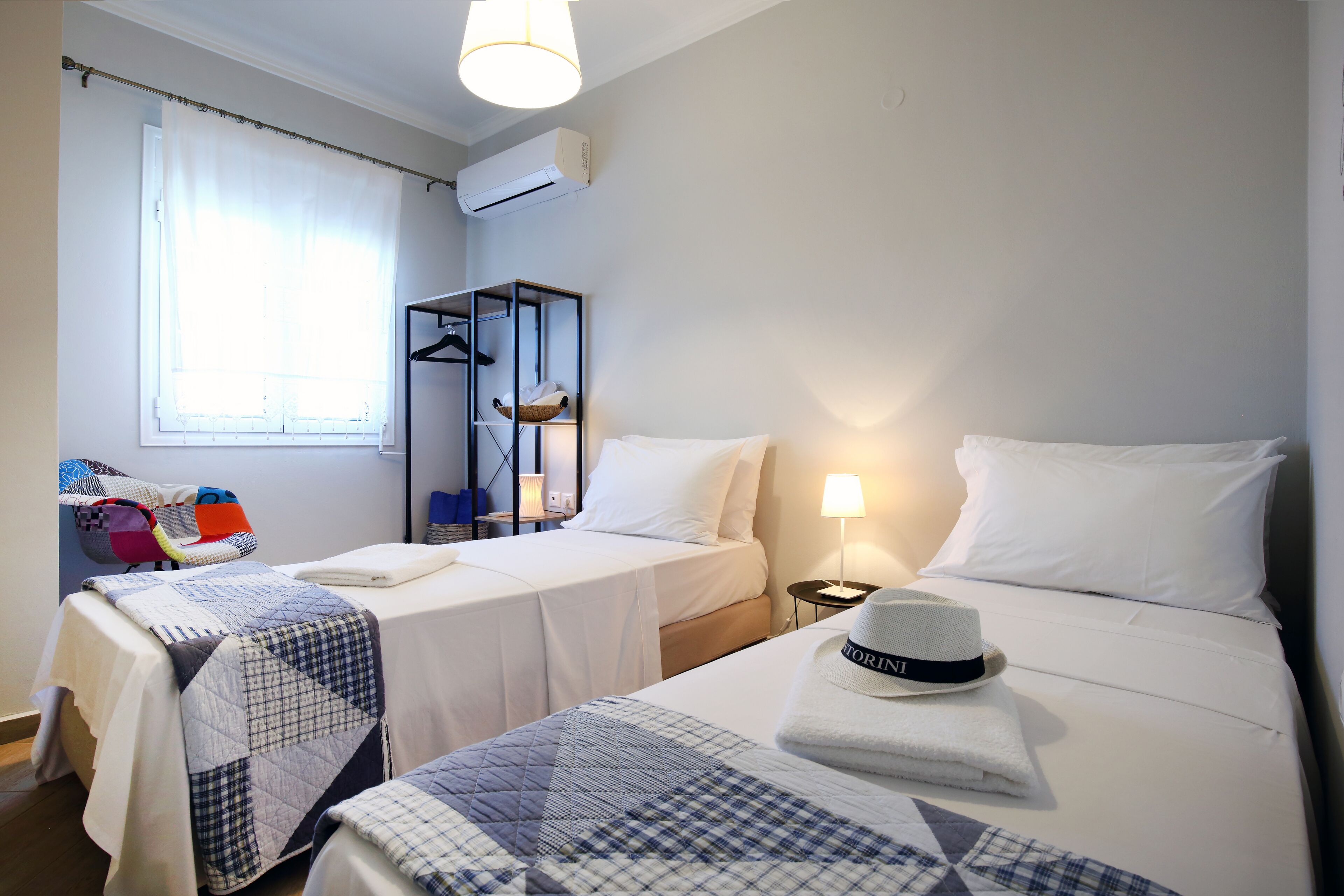 Habitación de hotel con dos camas, un armario, una lámpara de noche y una ventana con cortinas.