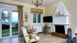 Una sala de estar con chimenea, televisor y vistas al exterior.