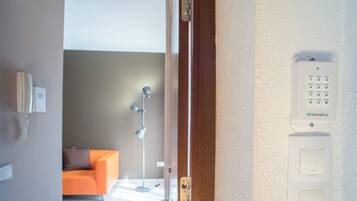 Une vue intérieure d’une chambre d’hôtel, avec une porte en bois, un téléphone blanc fixé au mur et un clavier numérique.