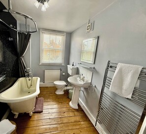 Une salle de bain équipée d’une baignoire, de toilettes, d’un lavabo et d’un porte-serviettes.