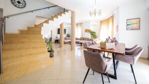 Un vaste espace de vie comprenant un escalier, une table à manger avec des chaises et un lustre.