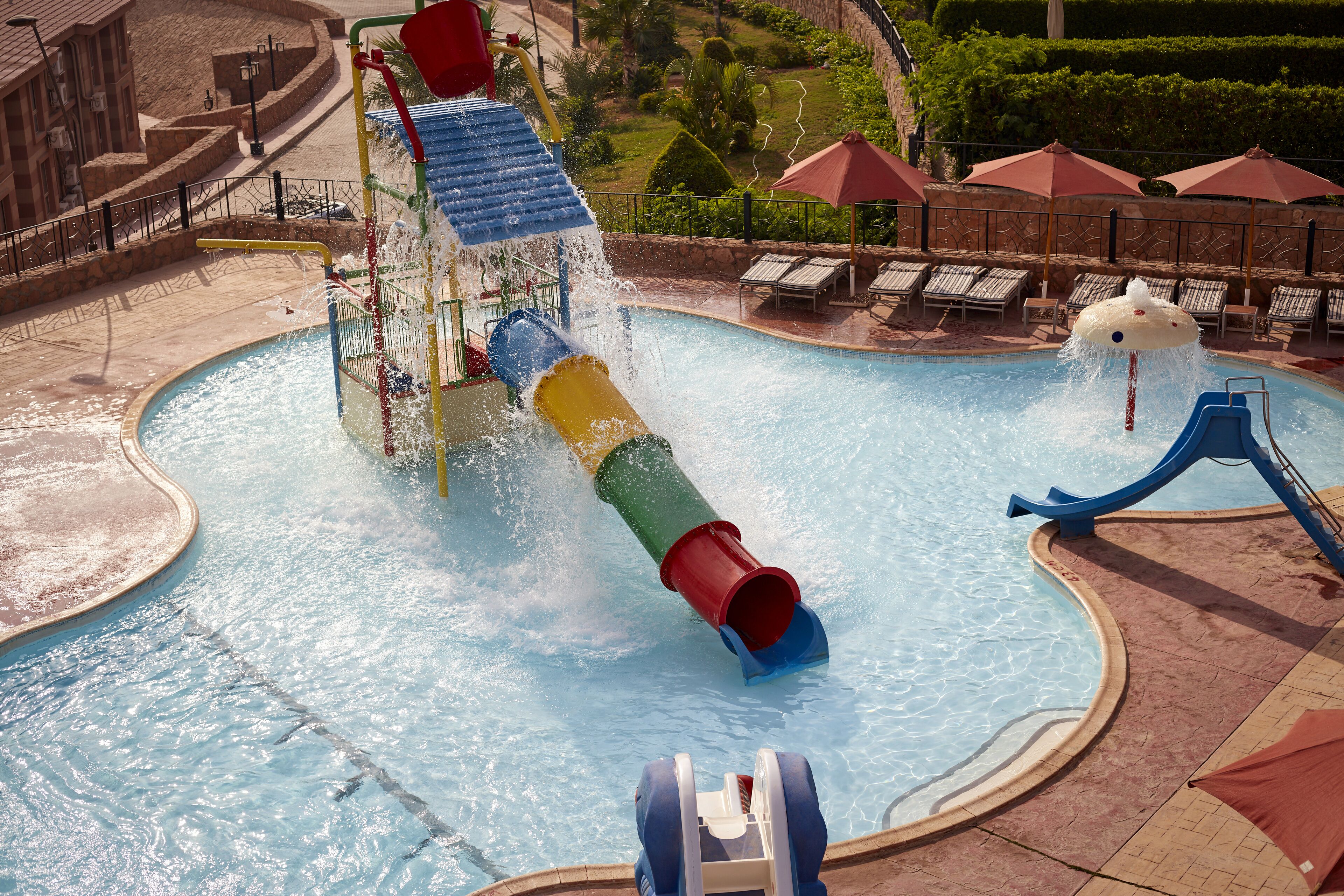 Parque acuático con tobogán de agua, piscina y sillas de descanso.