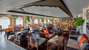 Un vestíbulo amplio con muebles de madera, grandes macetas y una zona de bar.